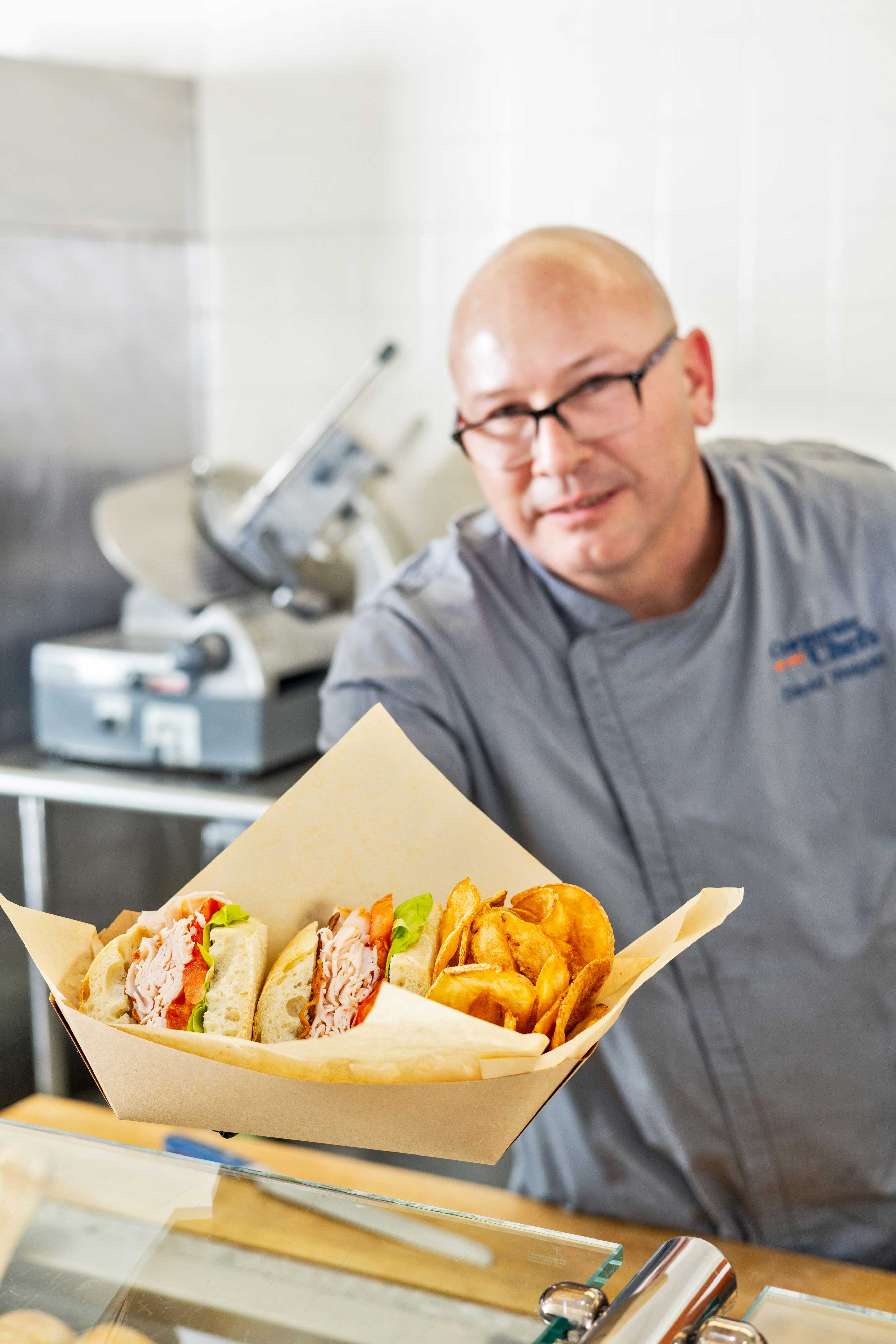 Employee handing sandwich and chips